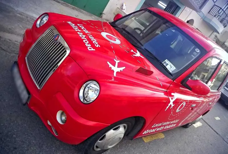 A red London-style taxi wrapped in printed Vodafone graphics